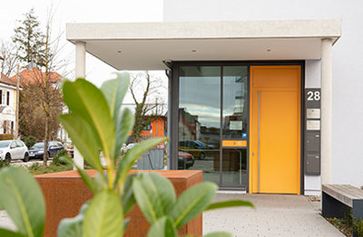Eingang Strahlentherapiepraxis Fürstenfeldbruck mit orangener Tür.
